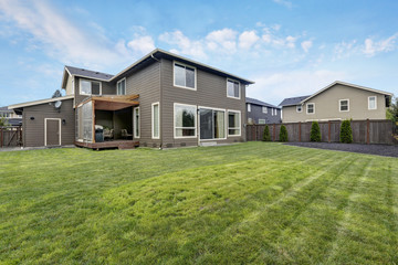 Grass filled back yard. Brown siding house exterior