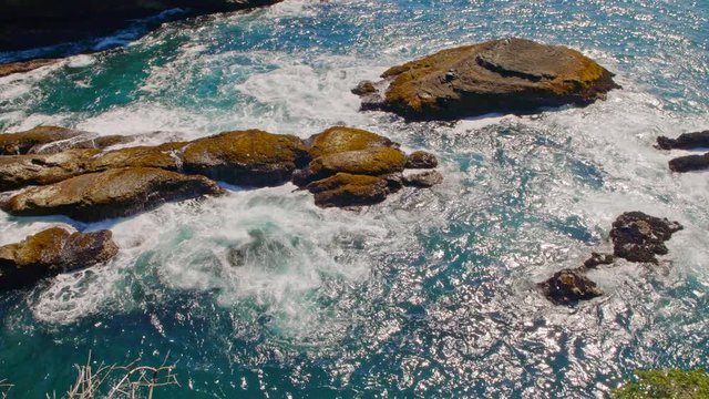 Gliding nature shot of picturesque and mysterious Cape Flattery bay by Pacific ocean coast with rich and colorful blue water, powerful waves and trees on a sunny, warm summer day