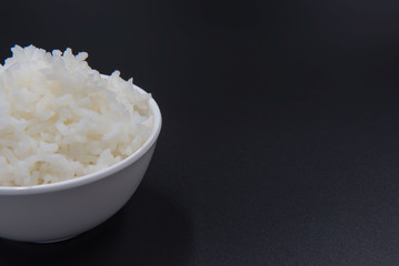 Cooked rice in a bowl on a black background.