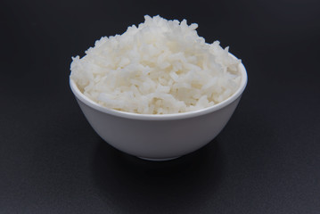Cooked rice in a bowl on a black background.