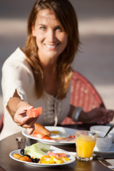 Obraz na płótnie Canvas femme souriante qui prend un petit déjeuner en extérieur