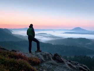Fototapeta premium Hiker man on rock watch over creamy mista and foggy morning landscape.