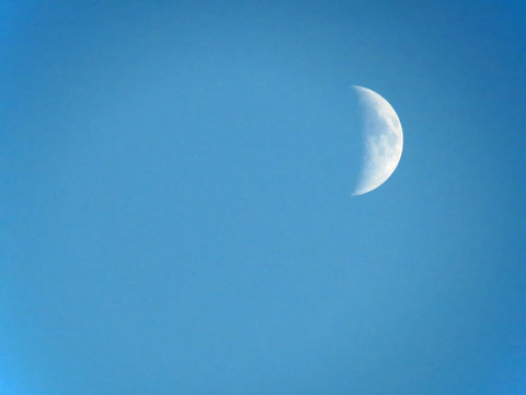 A crescent moon in a clear, blue sky at twilight, with space for text.