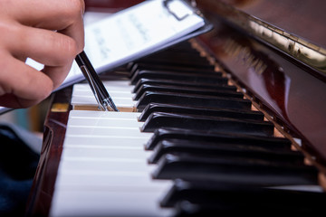 Holding piano song on a clipboard and playing piano with ballpen