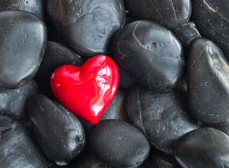 Red heart on black stones
