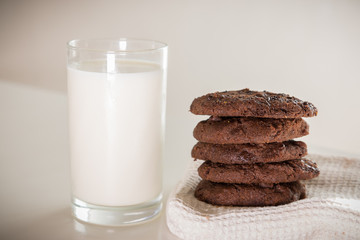 Milk in glass with stack of chocolate cookies