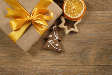 gift box with golden ribbon bow and christmas cookies on wood table