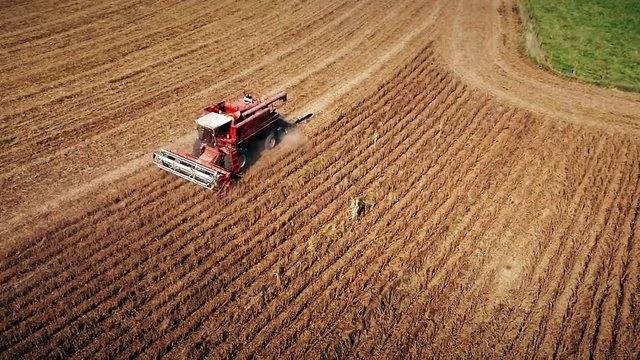 Aerial view on the combines and tractors working on the large soybean field in Kansas