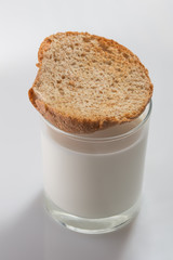 Toasted bread on top of glass with cow milk on white background