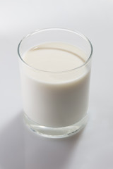 Colorless glass full of cow milk on white background