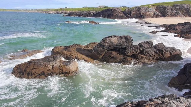 Beautiful turquoise water crashes into rocks at the shore of Clifden Bay, in Connemara, Ireland.