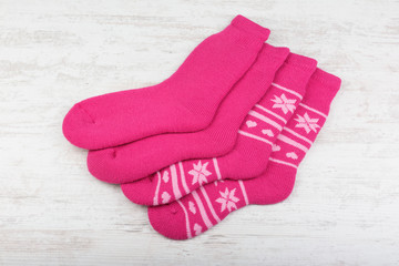 Pink woolen socks on white wooden background