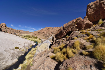 River flowing between mountains under a nice blue sky.