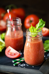 Fresh tomato and celery smoothie in a glass jar on a blask slate board with the ingredients © kuvona