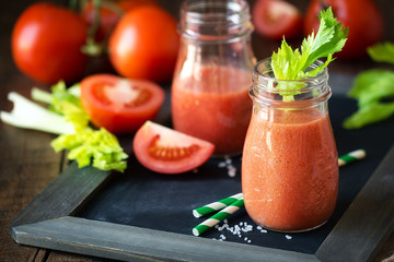 Fresh tomato and celery detox smoothie in a glass jar on a blask slate board
