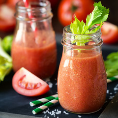 Fresh tomato and celery smoothie in a glass jar on a blask slate board with the ingredients © kuvona