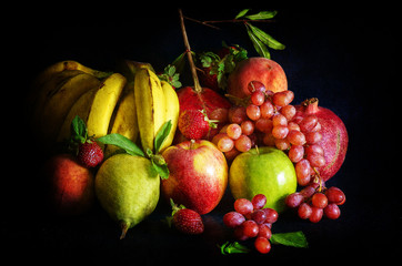 Still life with collection of fruits, bananas, apples, strawberries, grapes, pomegranate, pears, peach on black background.