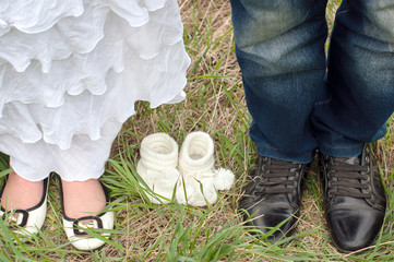 семейная пара в ожидании малыша, чуда. ноги мамы и папы и пинетки малыша. семья © mokeeva