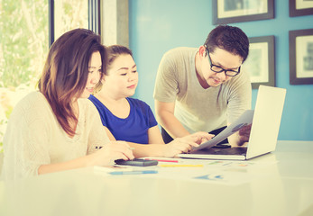Fototapeta premium Vintage style photo of two women and one man are working with at computer in modern office