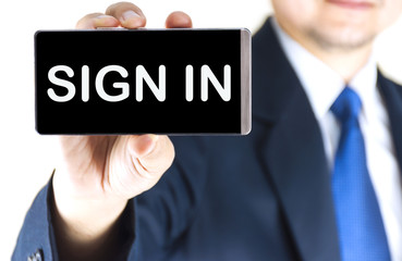 SIGN IN word on mobile phone screen in blurred young businessman hand over white background, business concept