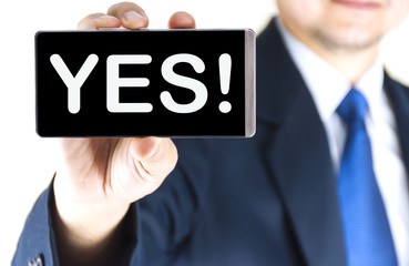 YES ! word on mobile phone screen in blurred young businessman hand over white background, business concept