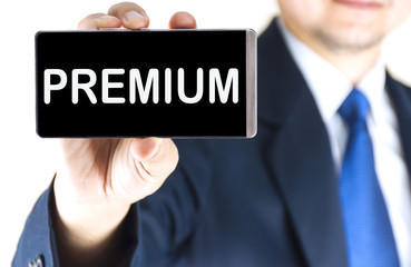 PREMIUM word on mobile phone screen in blurred young businessman hand over white background, business concept