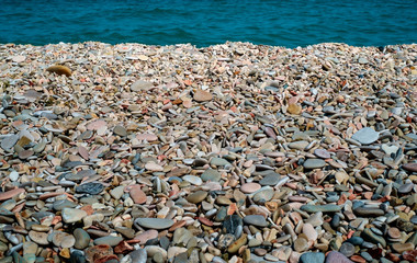 Pebbly beach detail. Blue sea on background