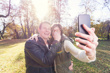 Couple having fun while taking Selfies in the Park