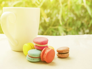 Warm tone of macaroon with coffee cup with warm sunlight, selective focused.