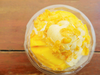 Top view of snow ice cream with mango and cornflakes topping on wooden table