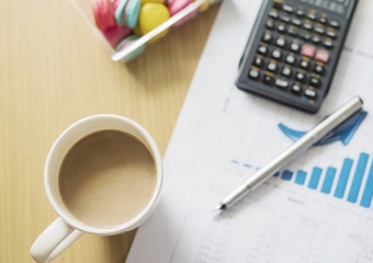 Business financial working concept, pen an calculator on growth bar graph with coffee cup and macaroon background selective focused