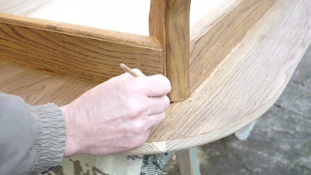 Carpenter is covering wooden table by lacquer. Worker making furniture and toning wood by paint
