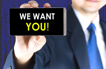 We want you word on mobile phone screen in blurred young businessman hand and digital technology background