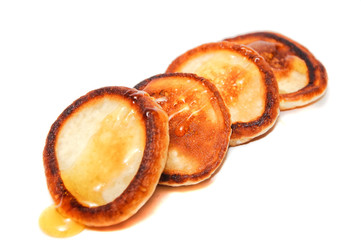 Pancakes drizzled with honey on a white background.