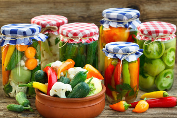 Canned And Fresh Vegetables. Canned Tomatoes, peppers And Pickled Cucumbers In Glass Jars On Wooden...