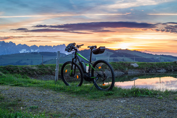 Fototapeta na wymiar eBike beim Sonnenaufgang mit Berge im Hintergrund