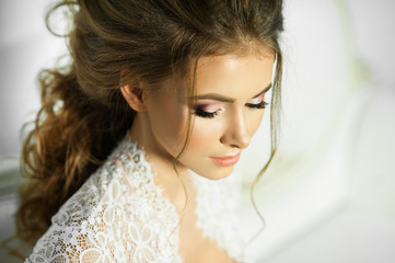 beautiful young girl with stylish hair and makeup in a white dress