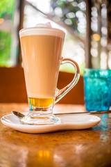 Coffee cappuccino with fluffy white milk on top. Placed on a wooden table ready to serve you.