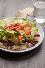 Taco Salad stacked on a bed of brown rice with tortilla chips and water
