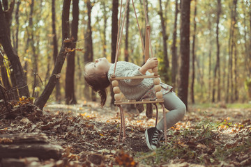 toddler girl on swing in the forest