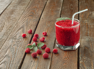 Raspberry smoothie in glass with straw, mint and fresh raspberry