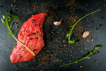 Fresh raw meat. Spices, chilli and garlic. Beef steak on a cutting board on a table. Top view, copy space