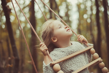 toddler girl on swing in the forest