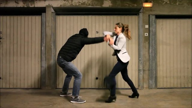 Man attacking a woman in a parking lot. Girl uses self-defense techniques to protect herself

