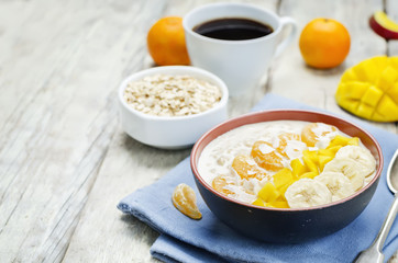 Oatmeal with mango, banana, tangerine oranges and coconut flakes