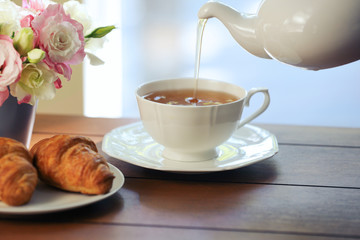 Pouring tea in cup on wooden table