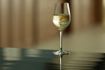 Glass with white wine on table