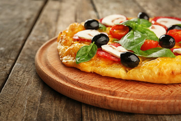 Delicious pizza with mushrooms, cherry tomatoes, olives and basil on wooden background