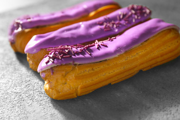 Delicious glazed eclairs on dark textured background