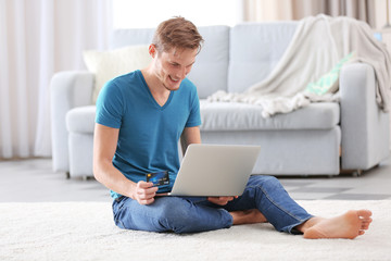 Young man lying on floor and making online shopping